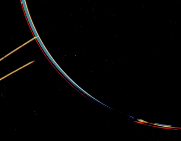 A dark image of Jupiter that shows one colorful curved blue ring and one colorful curved red ring extending off of Jupiter.