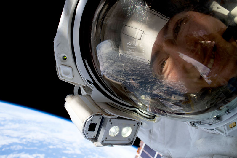 a woman in a space suit floating in space and looking directly into the camera