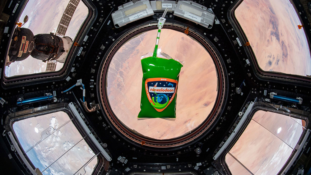 a bag of nickelodeon slime floating in front of a window on the international space station